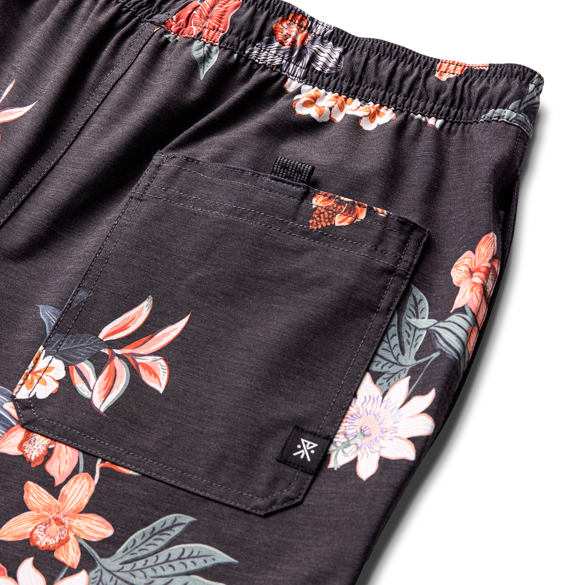 Assorted active and board shorts displayed amidst vibrant geraniums, highlighting Roark's outdoor and adventure-ready apparel.