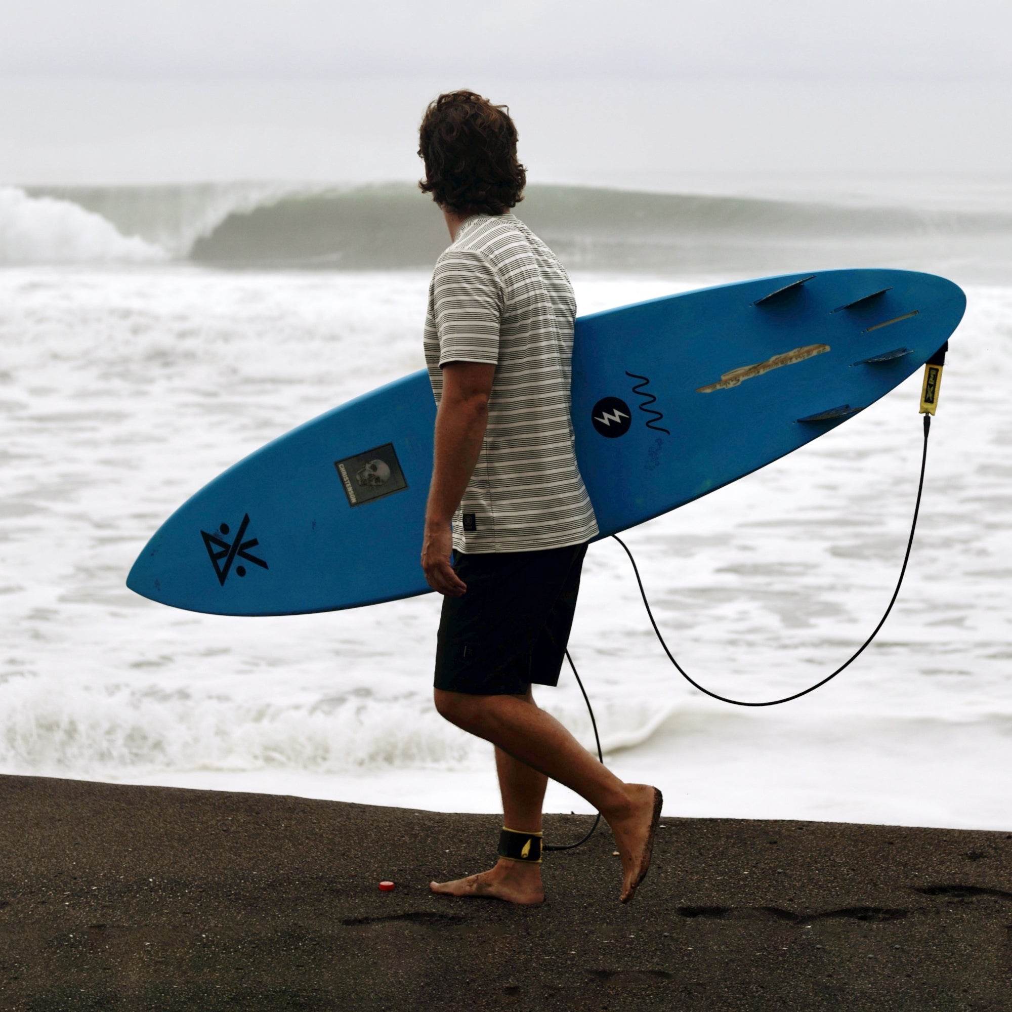 Surfer carrying a surfboard, ready for a water adventure, embodying Roark's spirit of exploration and outdoor sports.